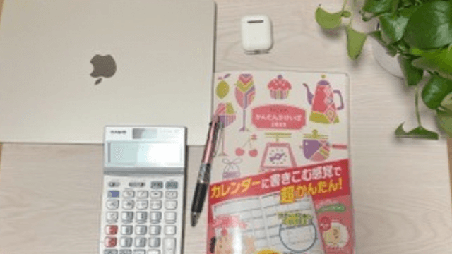 私の家計管理。パソコン、電卓、家計簿、イヤホンの写真